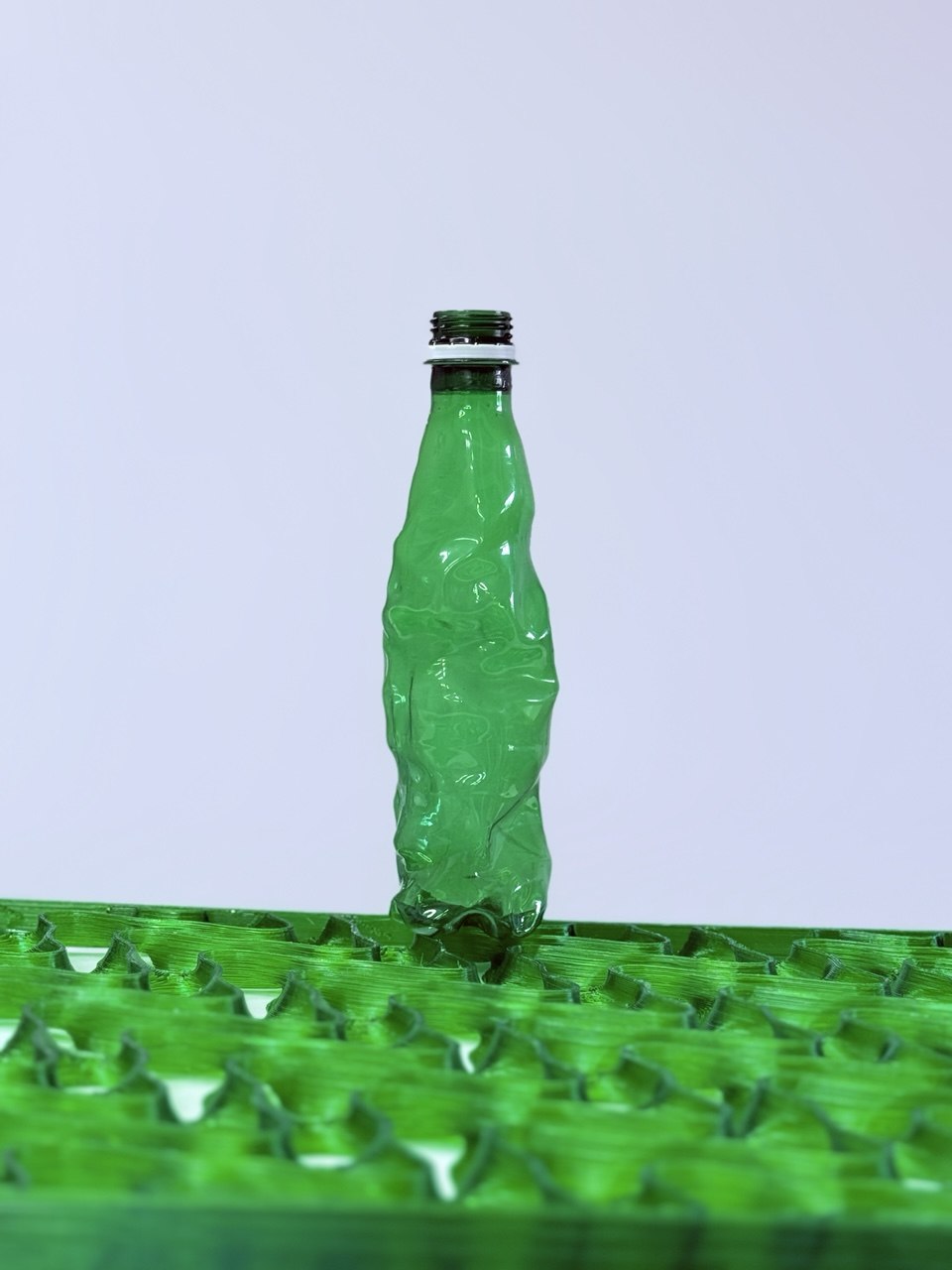 Green PET bottle standing on a matching green TacTile — input and output, same material, same color